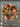 A round wreath with a autumnal design, including orange and yellow leaves, greenery, and blue berries, displayed on a dark door.