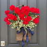 Red geraniums and white flowers in twig basket with navy ribbon